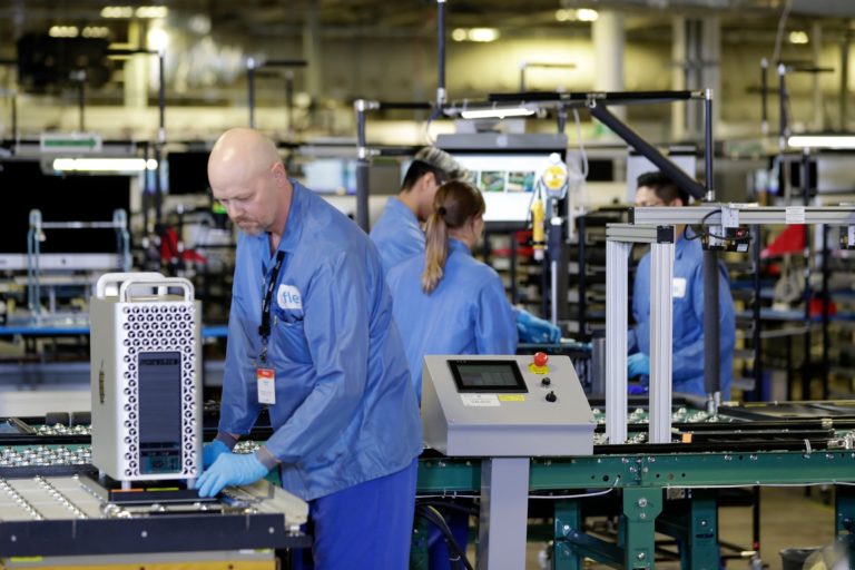 Workers in blue lab coats working on an assembly line in a factory, focusing on assembling electronic devices.