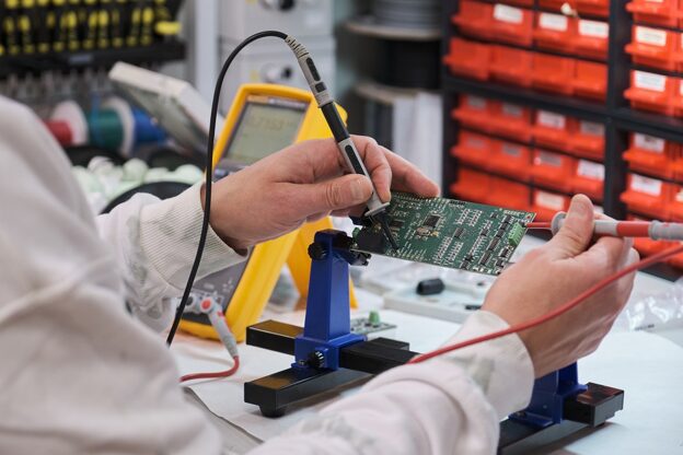 Technician testing a circuit board in a lab, ensuring quality control in the Production and Assembly of electronic components.