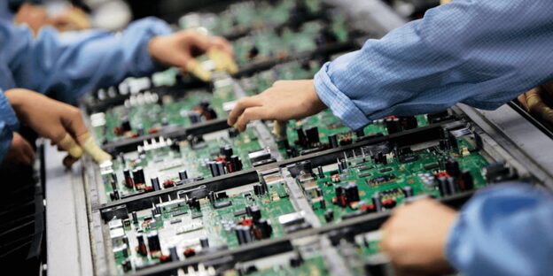 Technicians assembling circuit boards in a factory, highlighting Supply Chain Risk Management in electronics manufacturing.